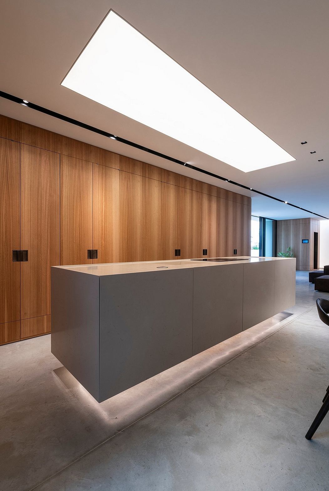 Modern and minimalist lobby with wooden panels, recessed lighting, and a clean rectangular reception desk.