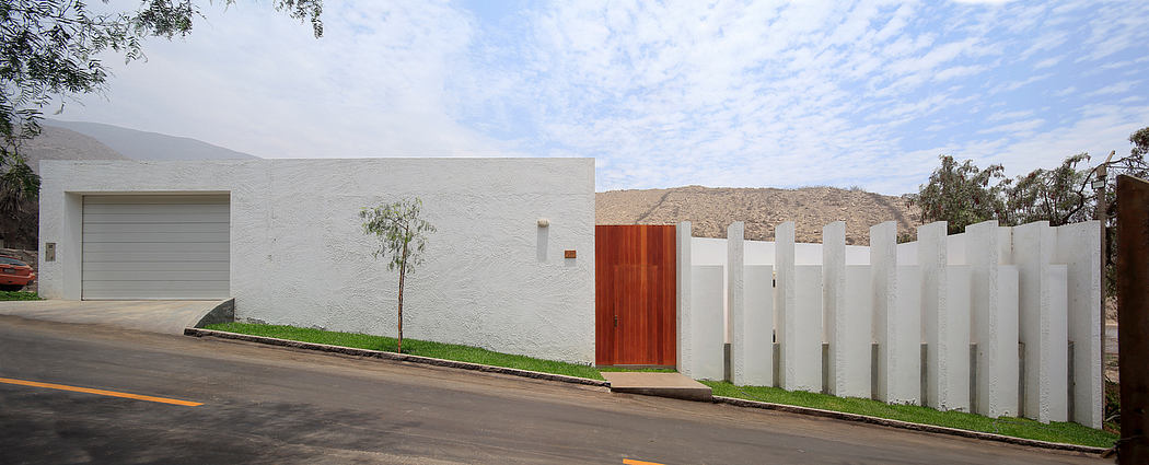 A modern, minimalist house with a white exterior, wooden accents, and a lush green lawn.
