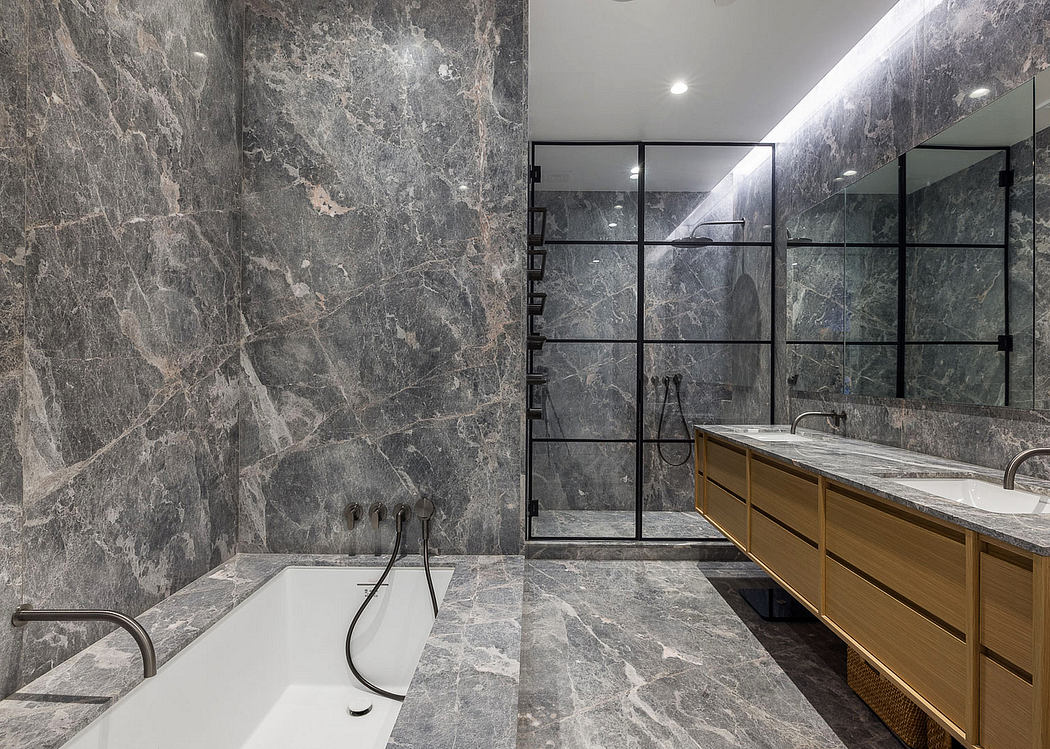 Luxurious bathroom with sleek marble walls, glass shower enclosure, and wooden cabinetry.