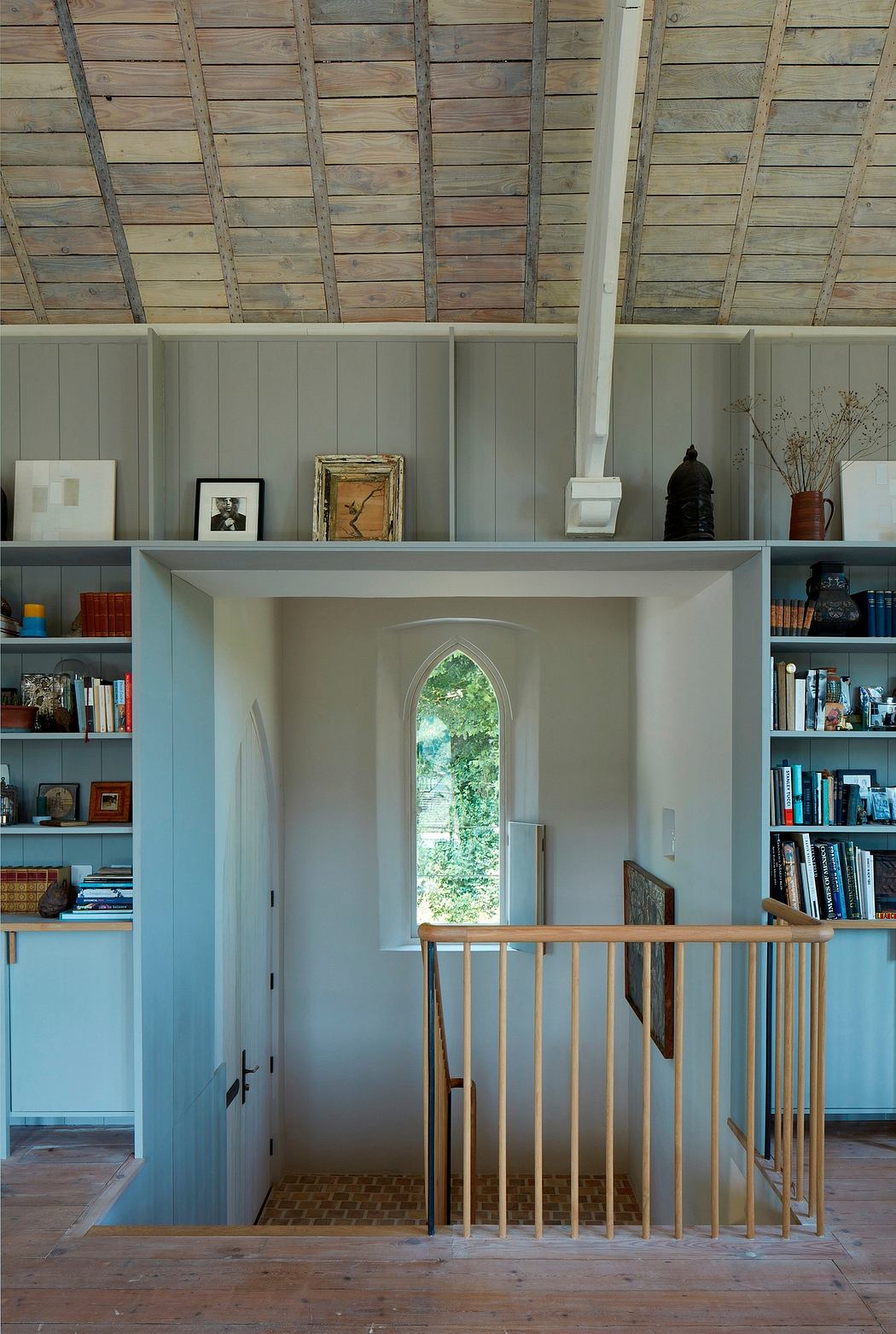 Rustic interior with arched window, built-in shelves, and wooden beams on the ceiling.