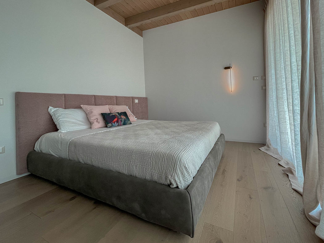 Cozy bedroom with wooden ceiling, soft gray tones, and recessed lighting for a relaxing ambiance.