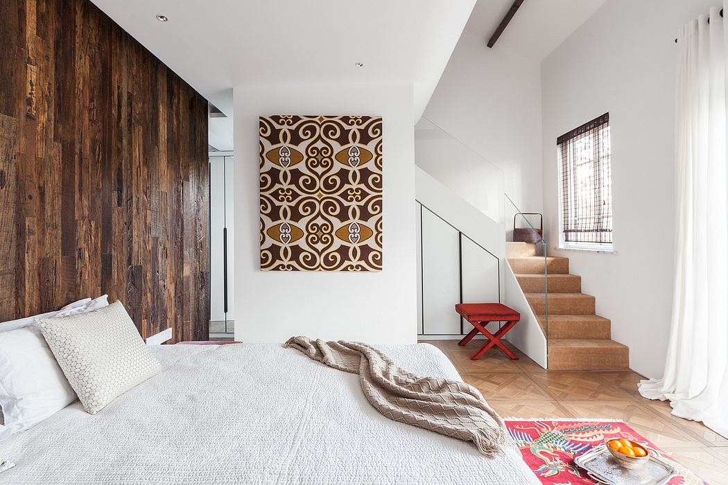 Contemporary bedroom with textured wooden accent wall, modern artwork, and stairs leading to upper level.