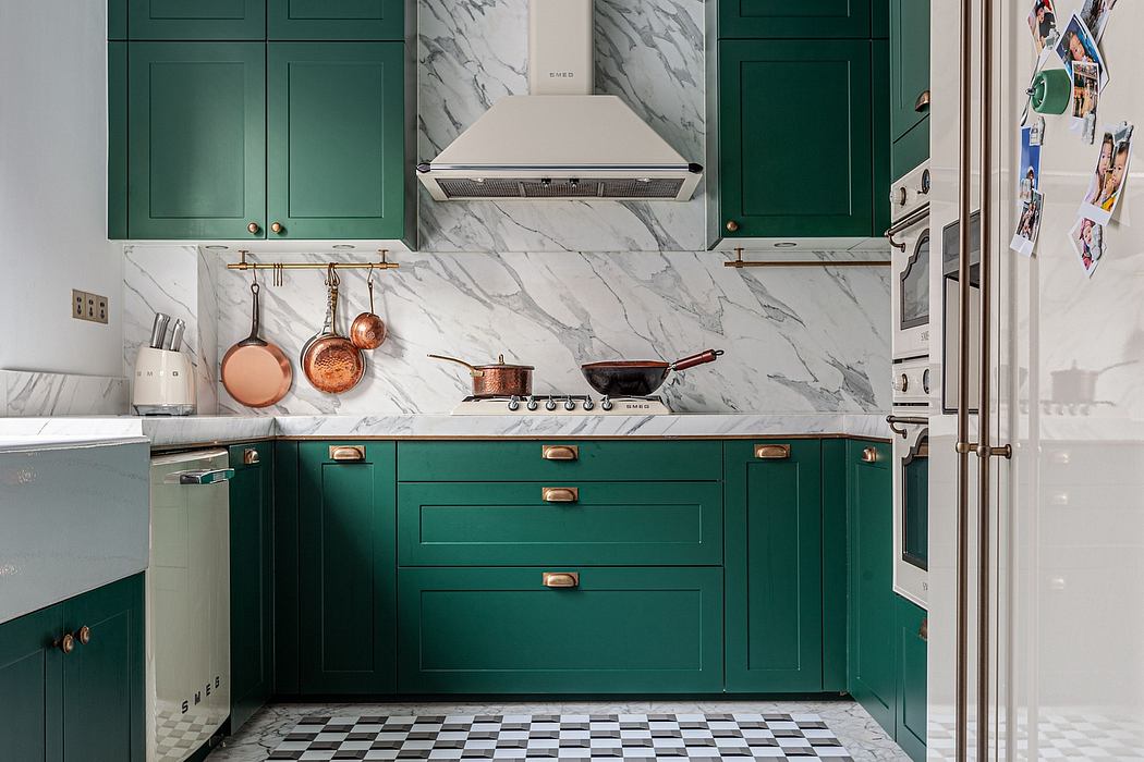 A stylish kitchen with rich emerald green cabinetry, marble backsplash, and copper cookware.