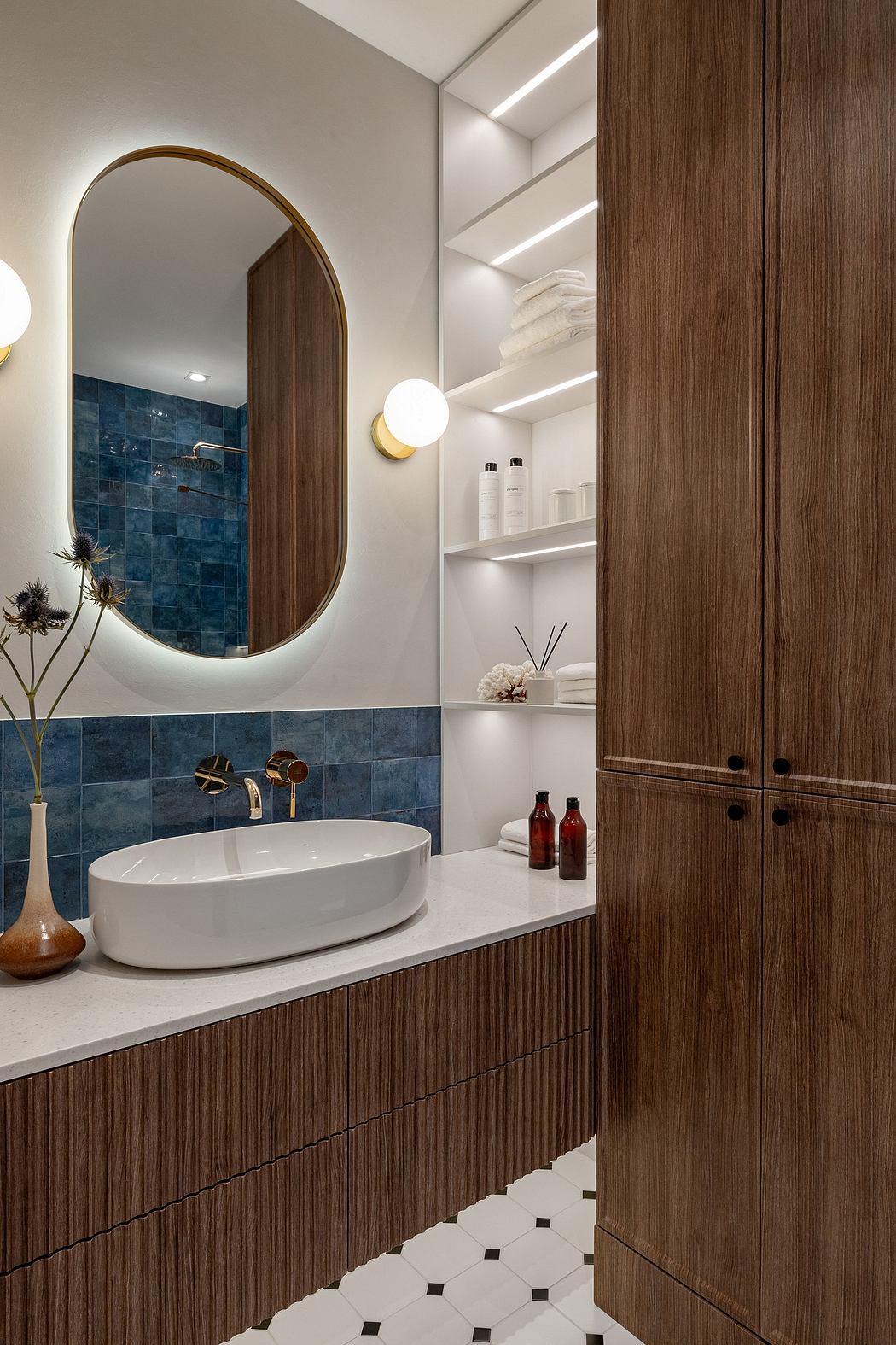 Elegant bathroom with oval mirror, wooden vanity, and blue tile backsplash.