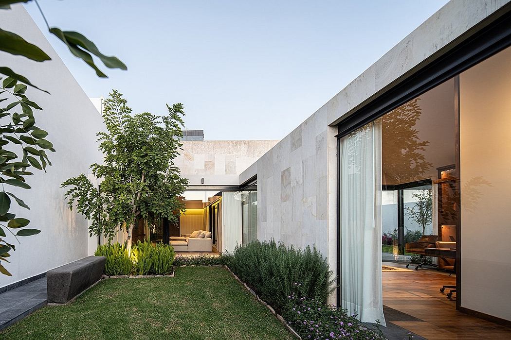 Modern residential architecture with landscaped courtyard and glass walls leading to interior.