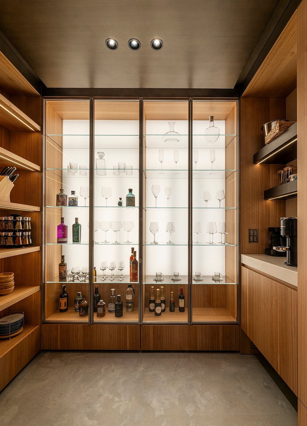 Elegant glass-fronted cabinetry showcases wine bottles and glassware in this stylish interior.