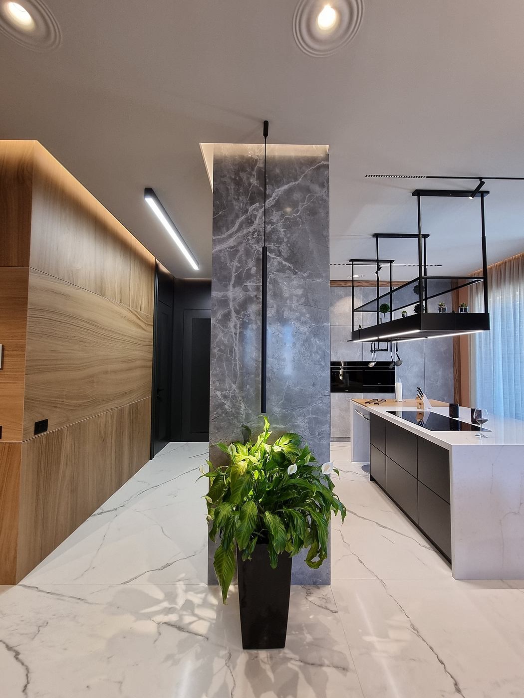 A contemporary kitchen with sleek marble surfaces, recessed lighting, and a hanging metal rack.