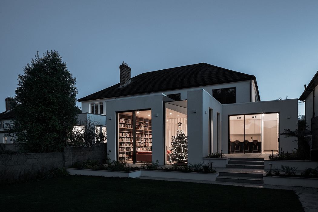 Modern, sleek house with glass walls, elevated entrance, and bookshelves visible through the windows.