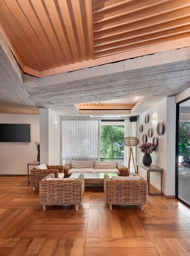 Warm wooden ceiling, wicker furniture, and textured wall art create a cozy, rustic ambiance.