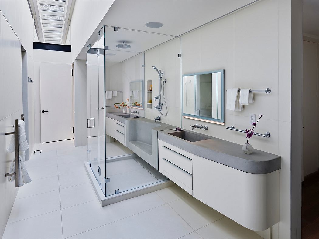 Spacious, modern bathroom with minimalist vanity, glass shower, and recessed lighting.