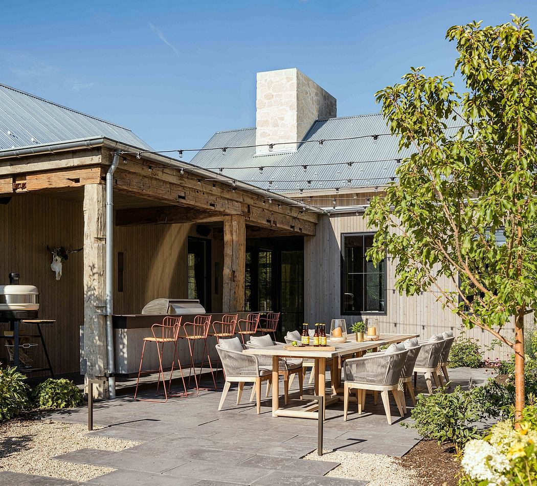 A rustic outdoor dining area with wooden beams, metal chairs, and a stone chimney.