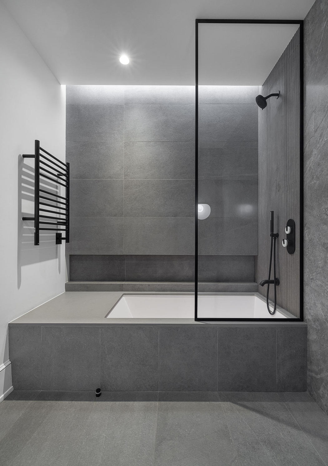 Sleek, modern bathroom with minimalist tile design, frameless glass shower, and built-in tub.