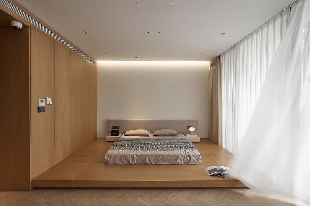 A minimalist bedroom with wooden paneling, a low-profile bed, and floor-to-ceiling curtains.