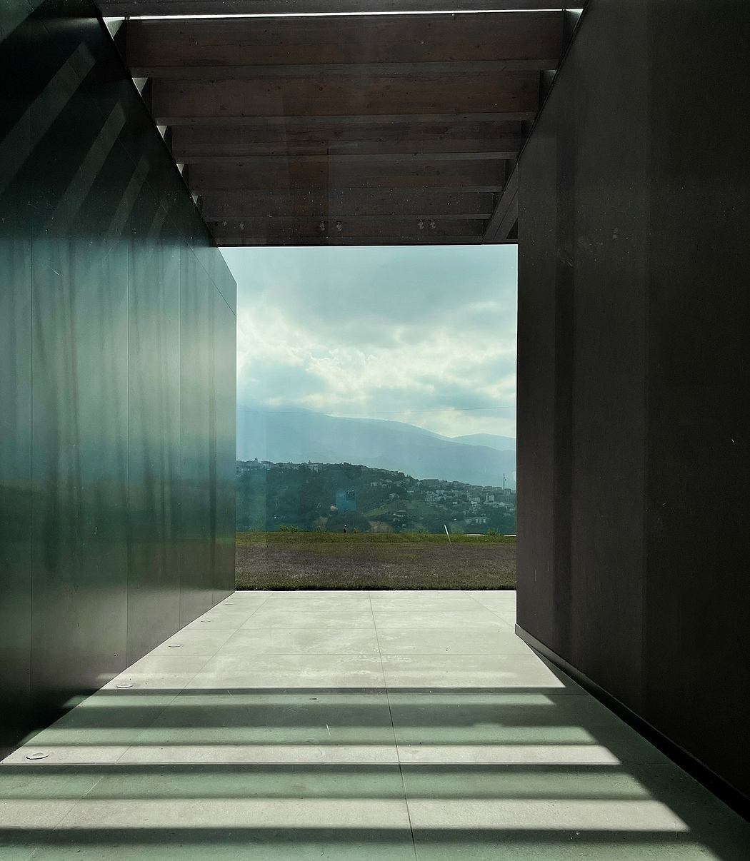 A concrete platform with wooden beams frames a mountainous landscape beyond.