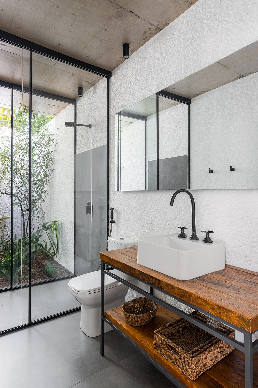 Sleek, modern bathroom with concrete walls, glass shower, and wooden vanity.