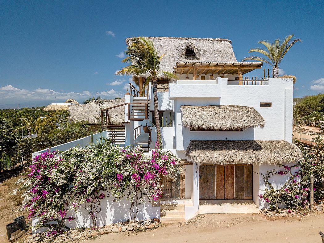 Tropical villa with thatched roofs, white walls, and vibrant bougainvillea blooms.