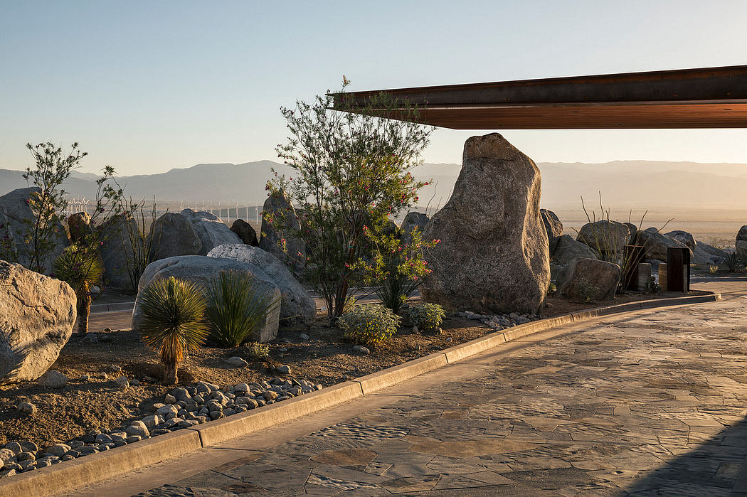 A desert landscape with large rocks, plants, and a wooden structure creating a serene atmosphere.