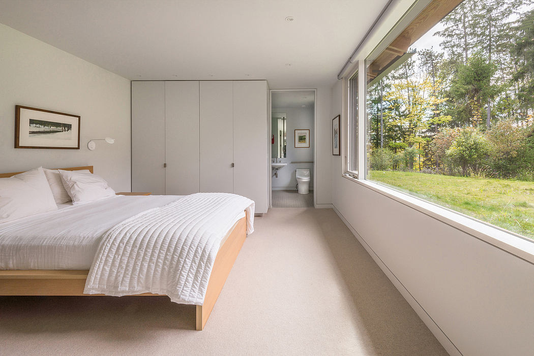 Spacious bedroom with minimalist furnishings, large window overlooking lush greenery.