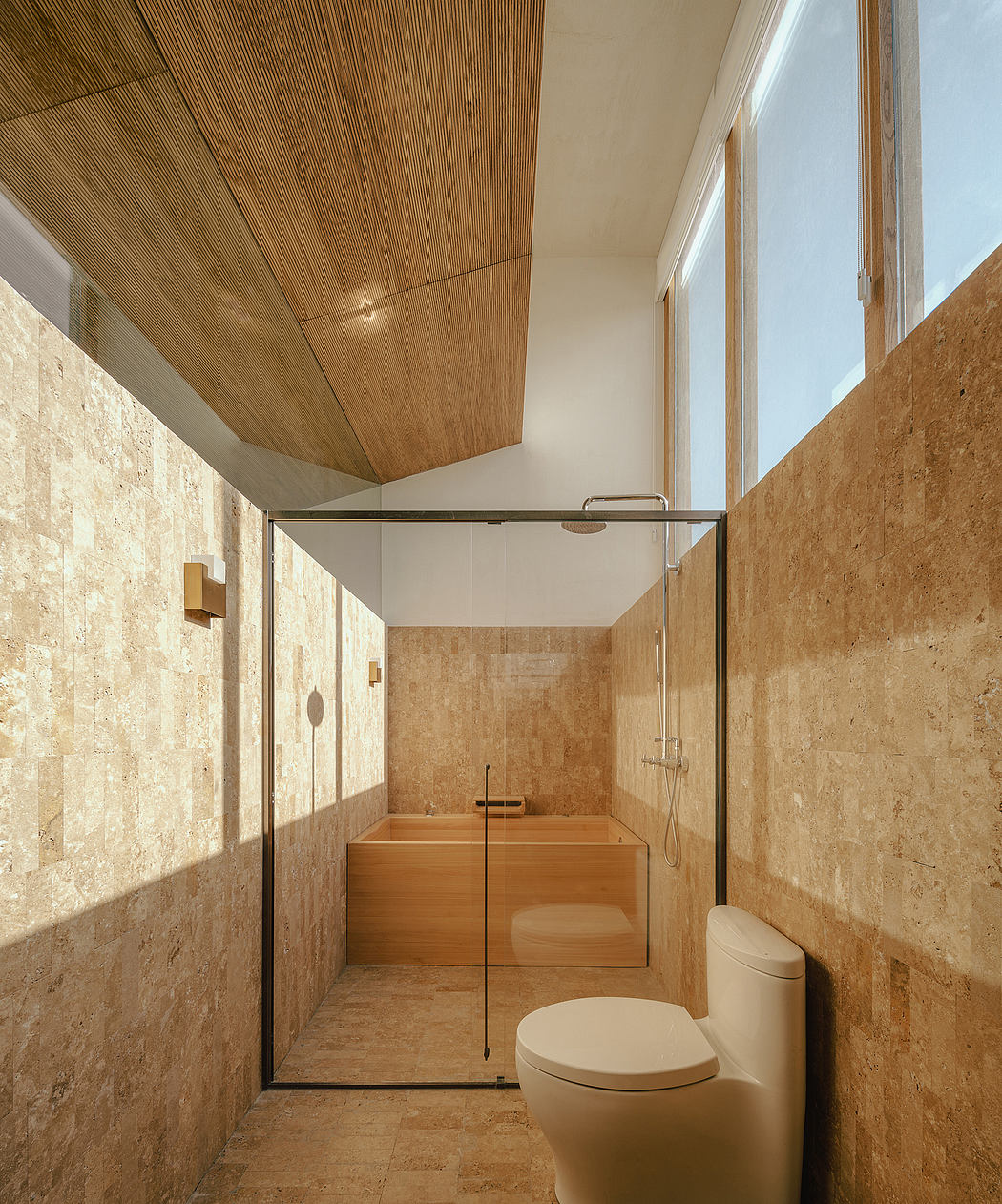 A bathroom with wooden paneled ceiling, stone walls, and a minimalist wooden tub.