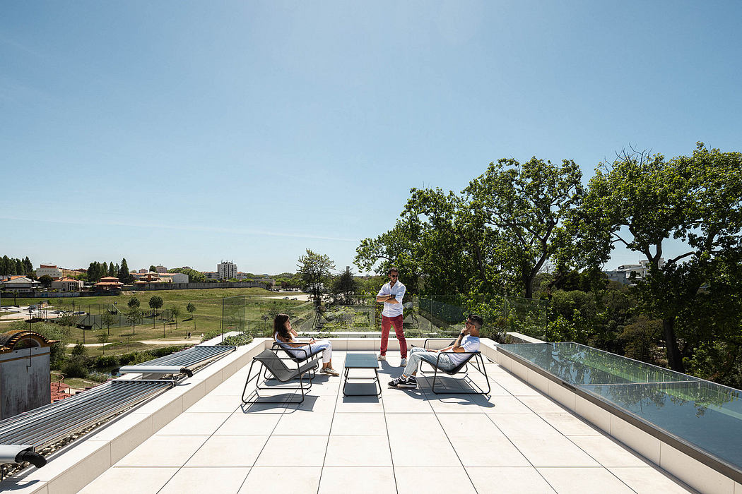 Expansive rooftop terrace with minimalist furniture, glass railing, and lush greenery.