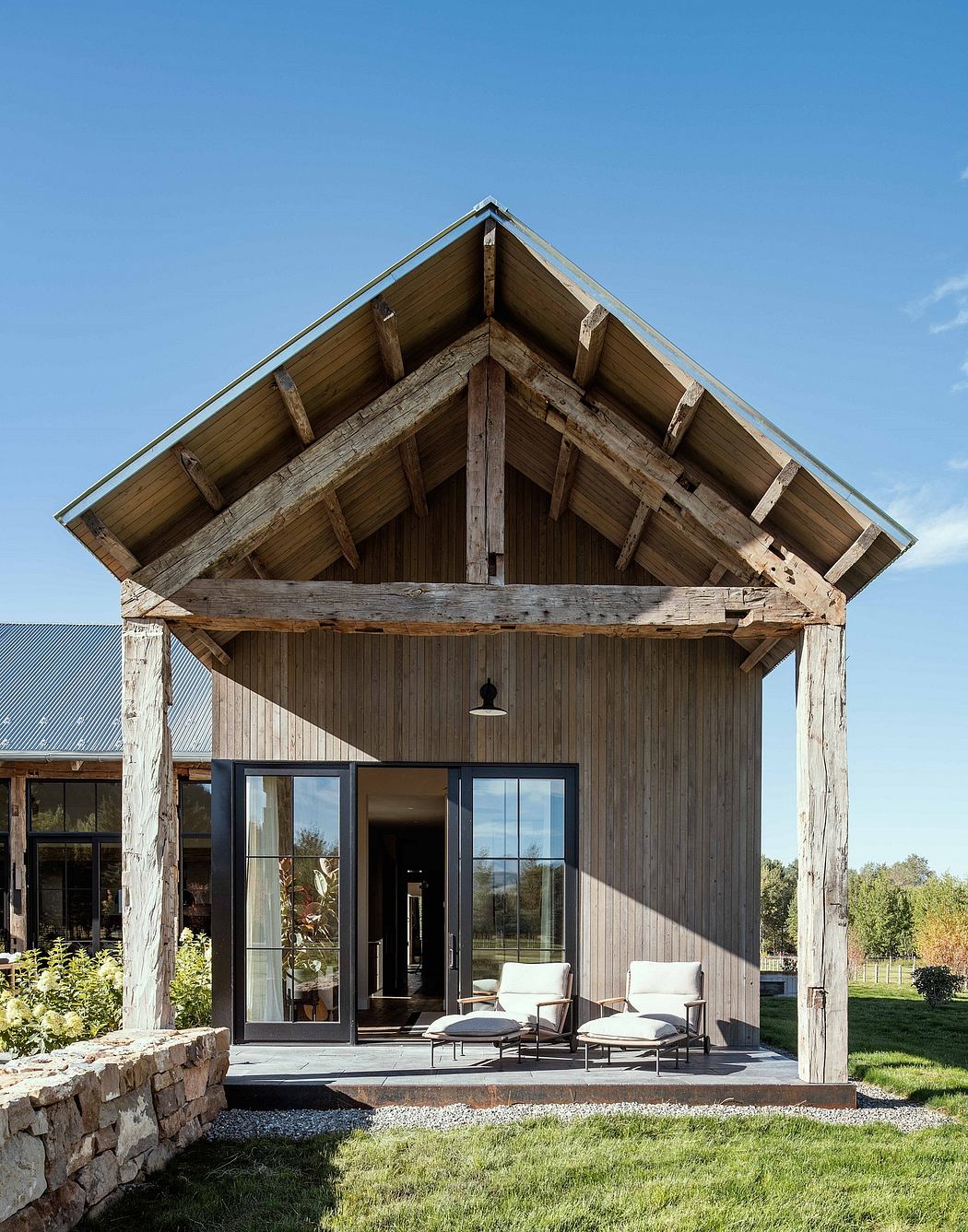 A rustic wooden cabin with a slanted roof, large windows, and patio seating.