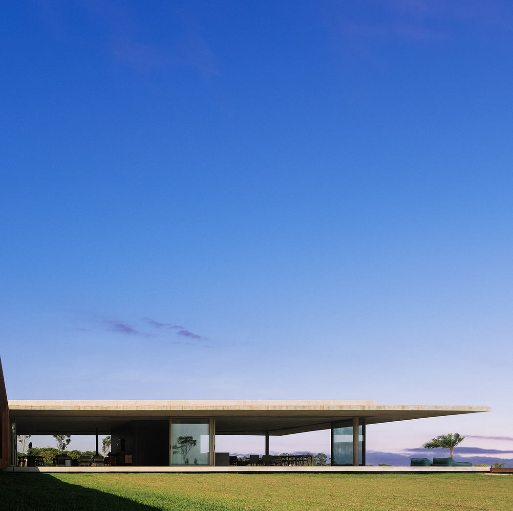 Modern architectural design with expansive glass windows, covered patio, and lush lawn.