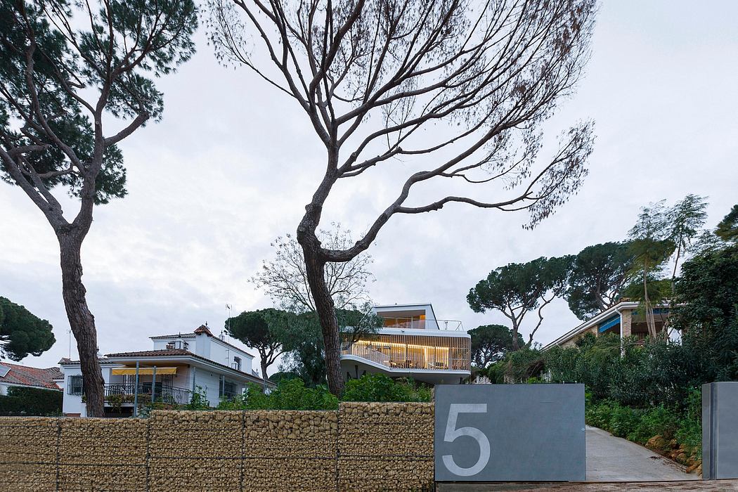 Residential buildings with balconies, trees, and concrete wall with address number 5.