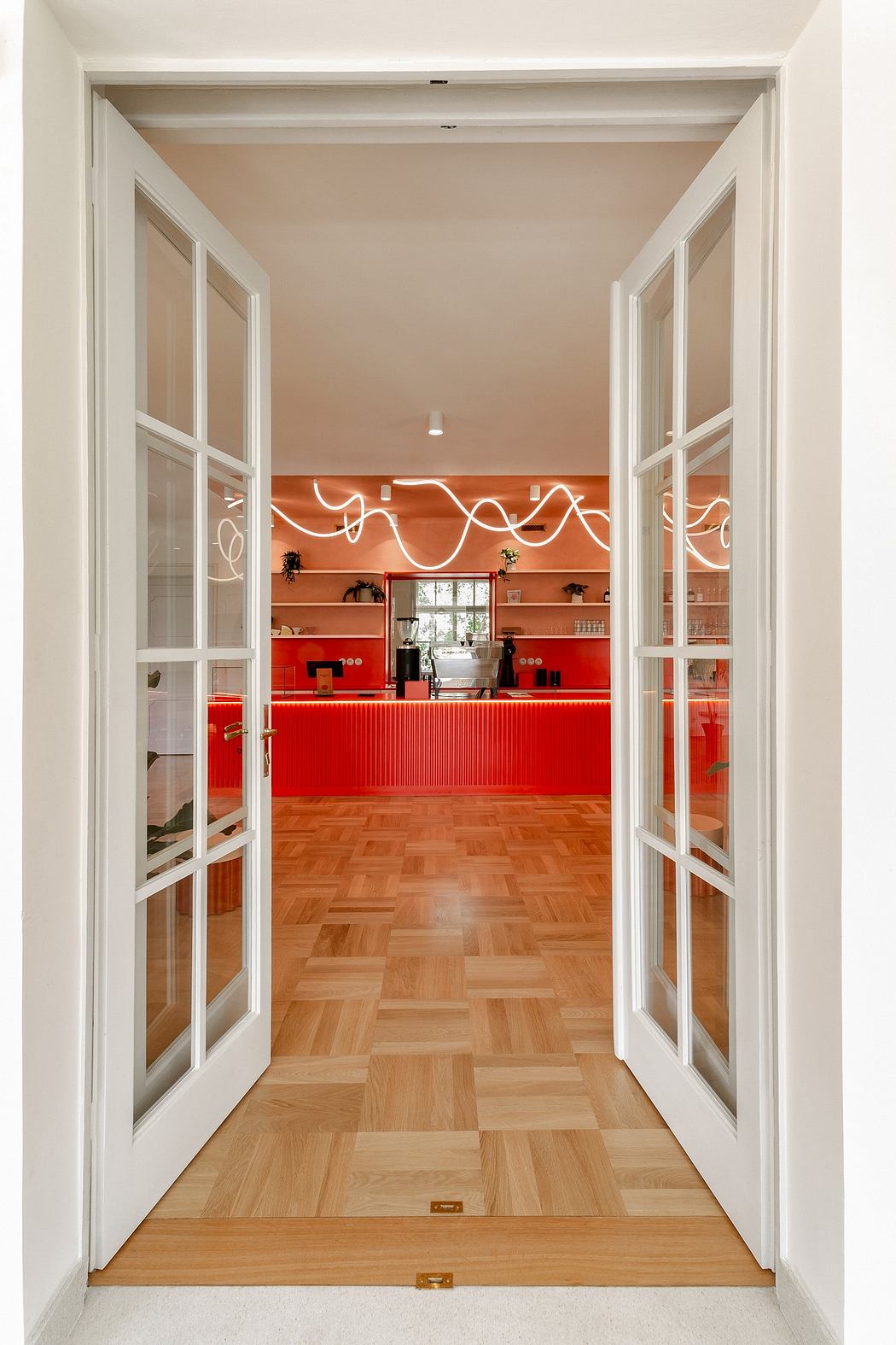 Bright, modern kitchen design with vibrant red cabinetry, hardwood flooring, and sleek white walls.