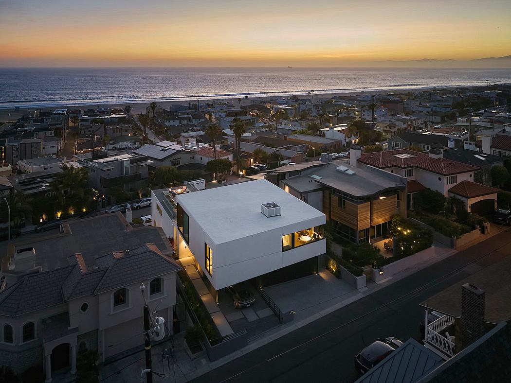 Aerial view of a modern, minimalist residence at sunset with surrounding buildings.