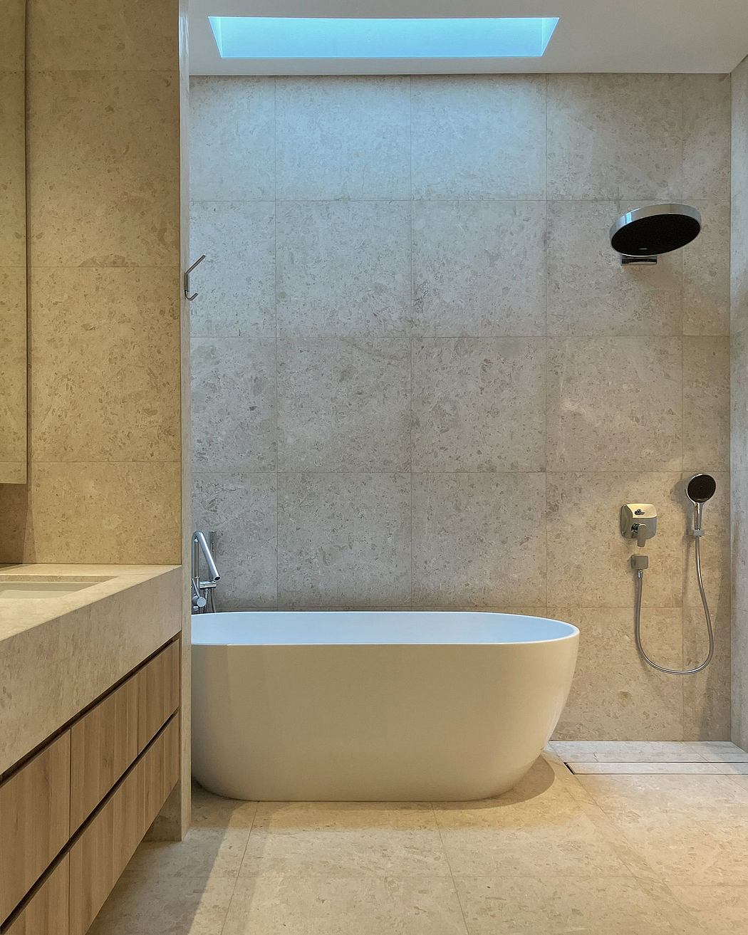 A minimalist bathroom with sleek marble tiles, a freestanding tub, and recessed lighting.