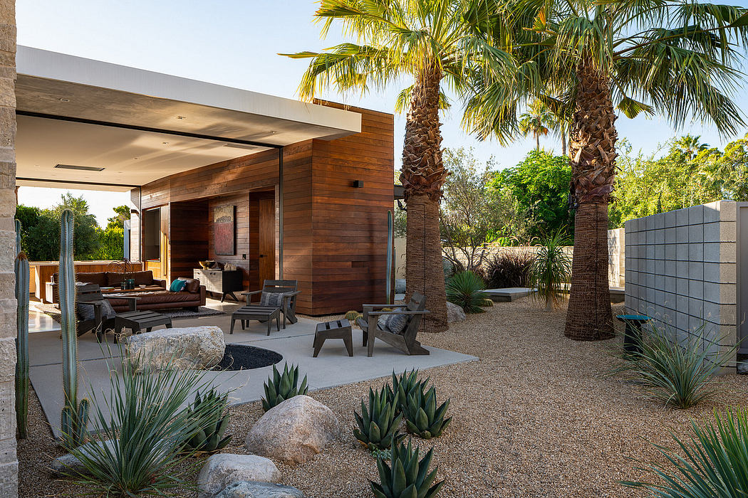 Modern desert oasis with natural stone, wood-clad exterior, and lush palm trees.