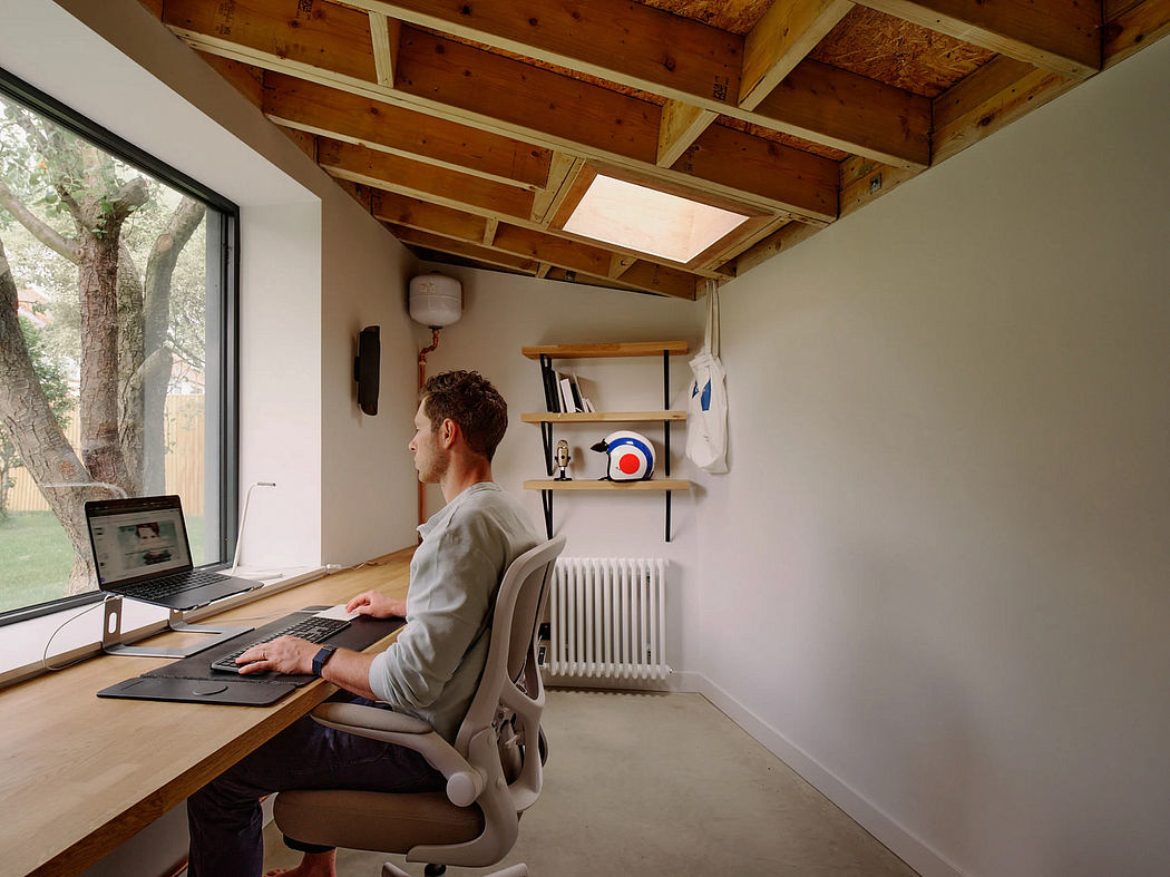A cozy, rustic home office with wooden ceiling beams, shelving, and a sleek computer workstation.