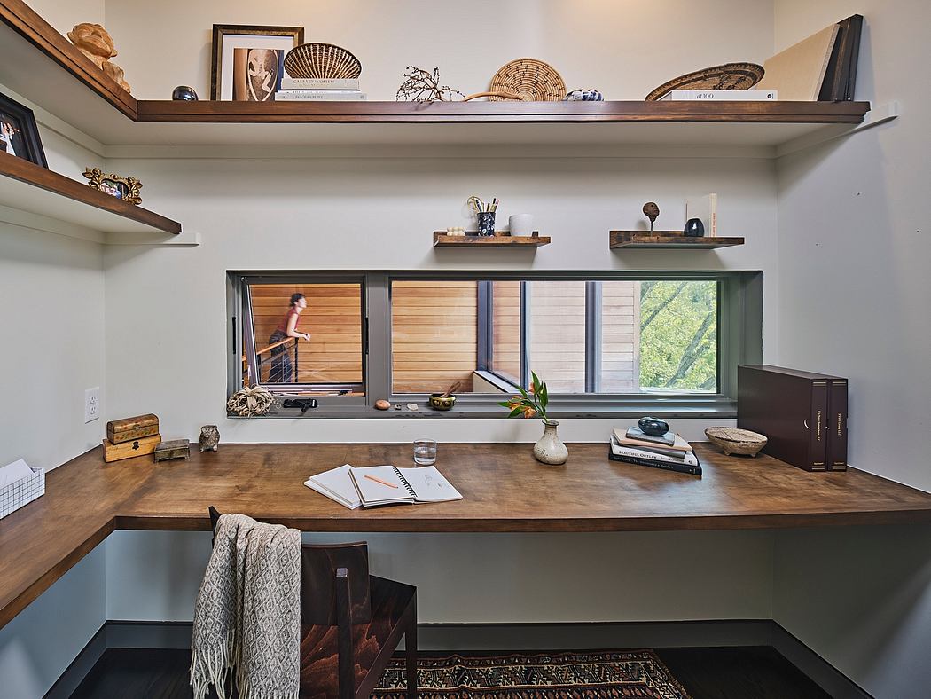 A cozy, stylish home office with wooden shelves, a large desk, and natural lighting.