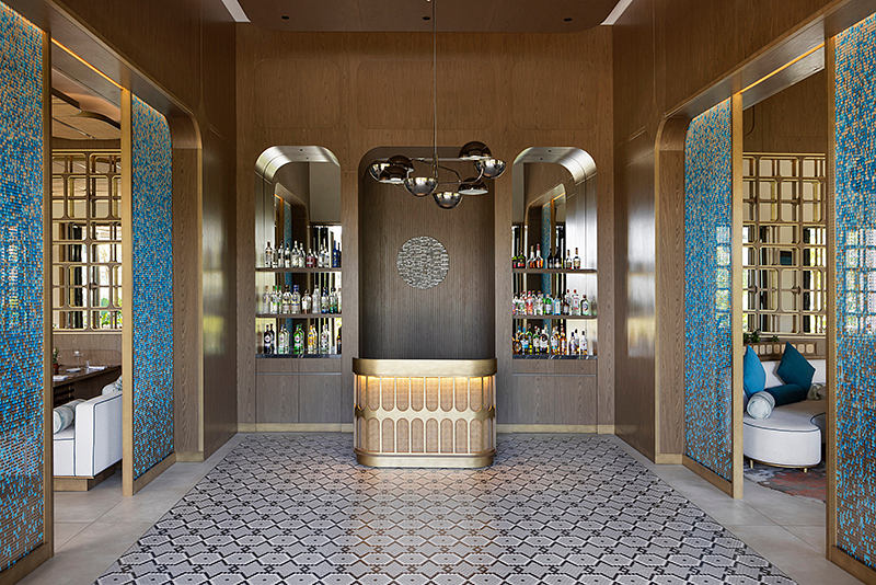 A lavish interior with a grand bar, intricate mosaic tiles, and a modern lighting fixture.