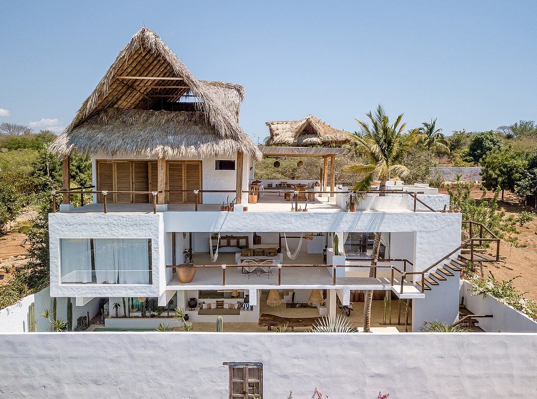 Modern villa with thatched roofs, glass walls, and multilevel outdoor living spaces.