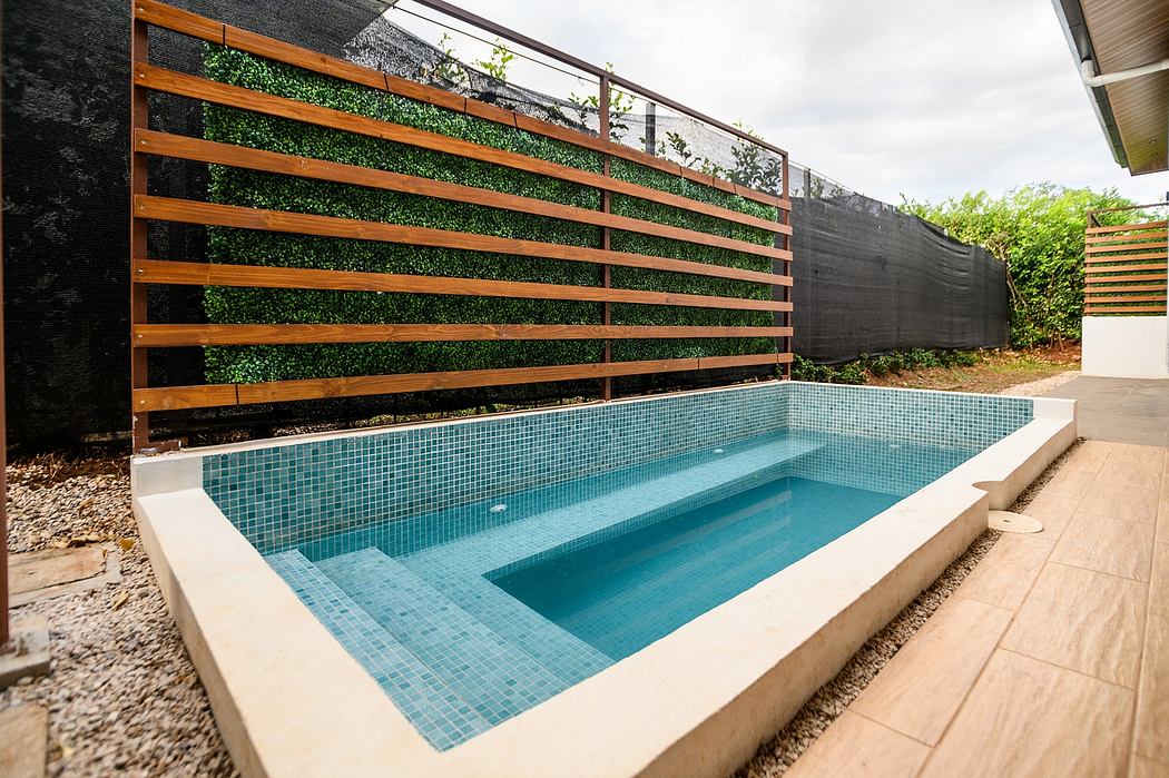 Modern backyard pool surrounded by wooden slat fence and lush greenery.