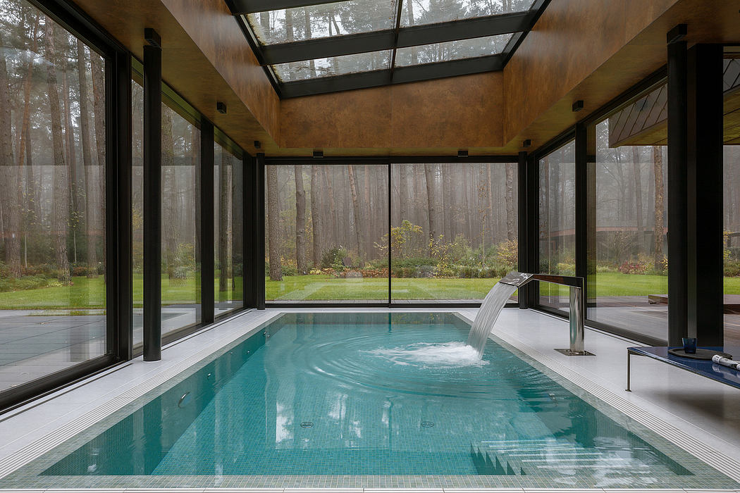 A modern and luxurious indoor pool surrounded by glass walls, showcasing the lush forest outside.
