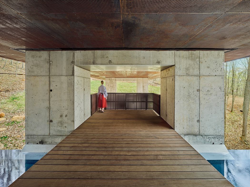 Concrete structure with wooden walkway and covered outdoor pavilion space.