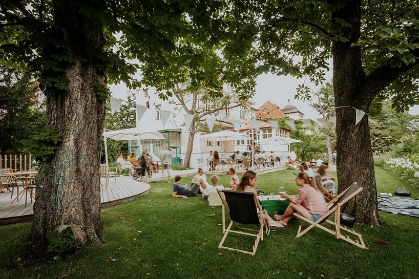 Lush, verdant setting with diverse seating areas, decking, and a charming, rustic building.