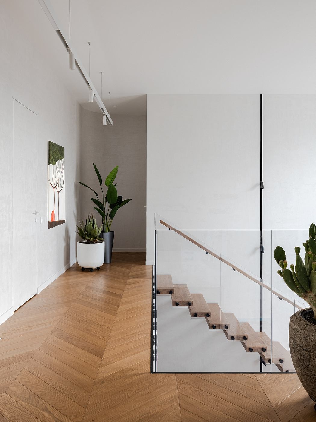 A minimalist staircase with a sleek glass railing and potted plants accentuating the interior.