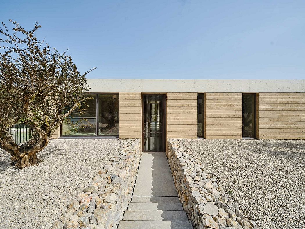 A modern, minimalist building with a wooden facade and large windows set amidst a gravel landscape.