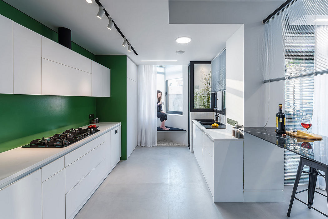 Modern kitchen design with sleek white cabinetry, green accent wall, and contrasting textures.