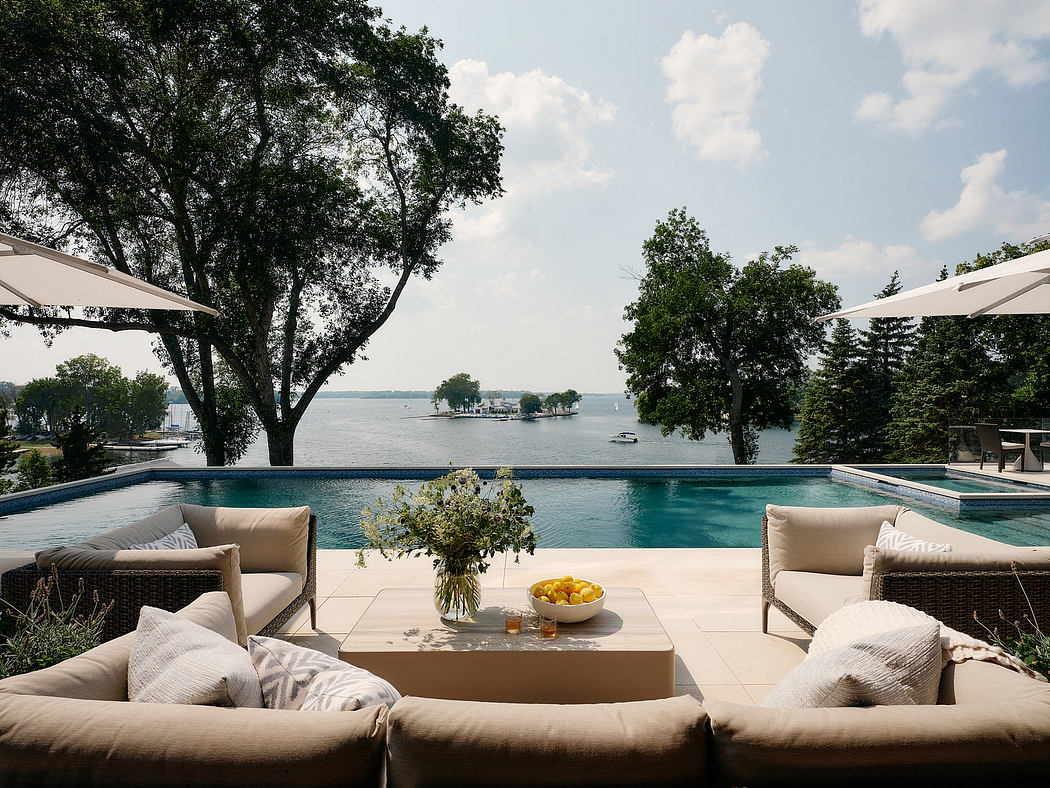Luxurious outdoor patio with infinity pool, lounge seating, and scenic lake view.