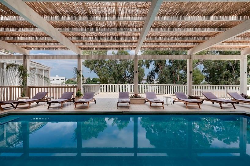 Inviting outdoor pool area with shaded lounge chairs and wooden deck under thatched roof.