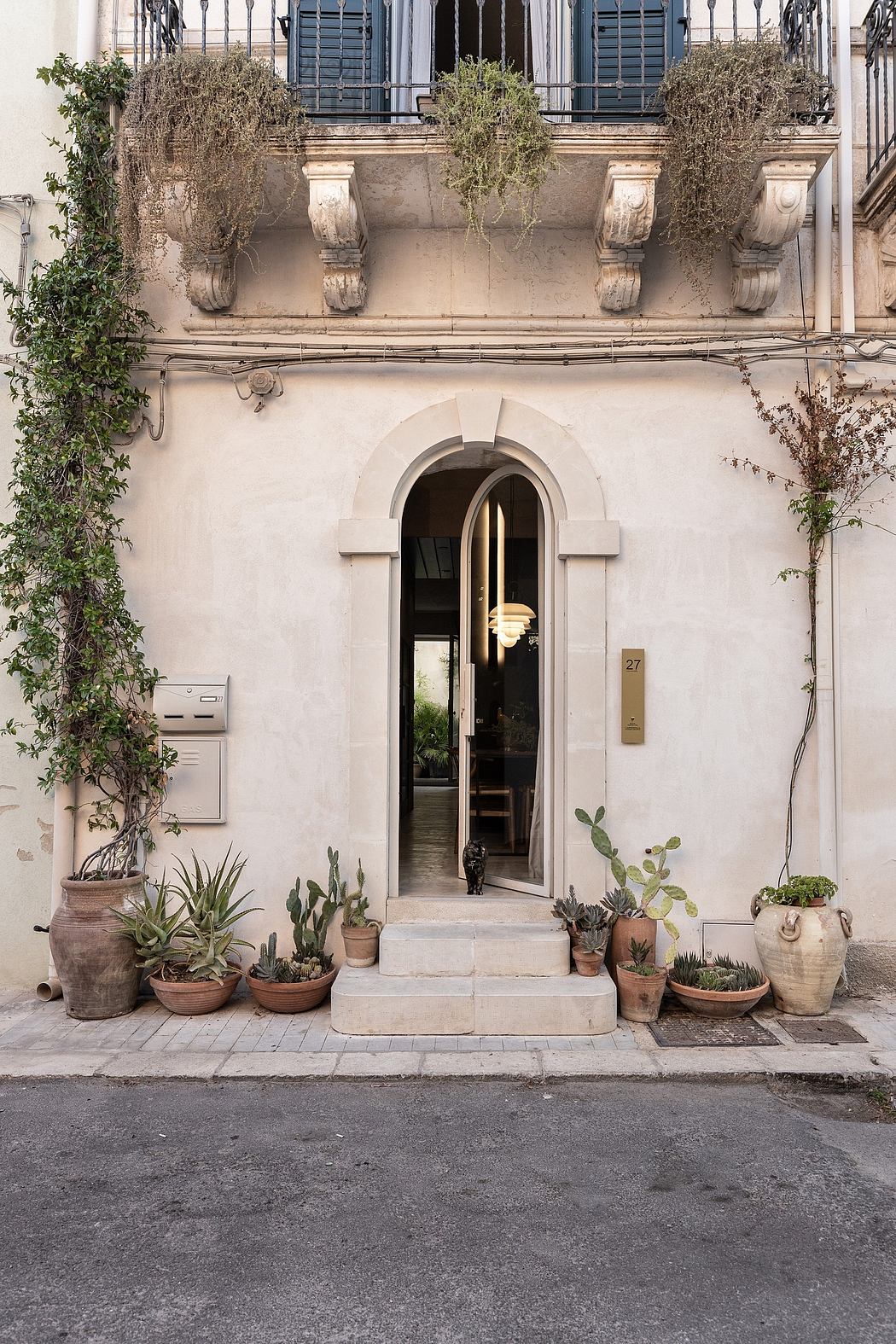 Ornate balcony, arched doorway, and potted plants adorning a charming Mediterranean exterior.