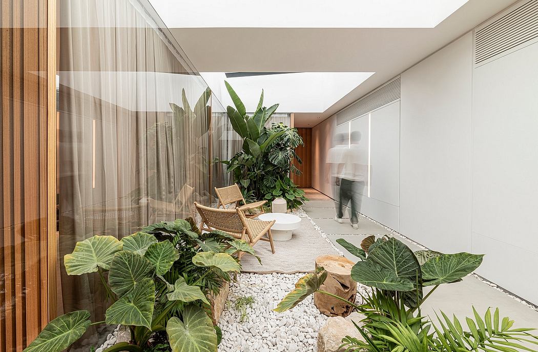 Serene indoor courtyard with lush greenery, neutral furniture, and a tranquil ambiance.