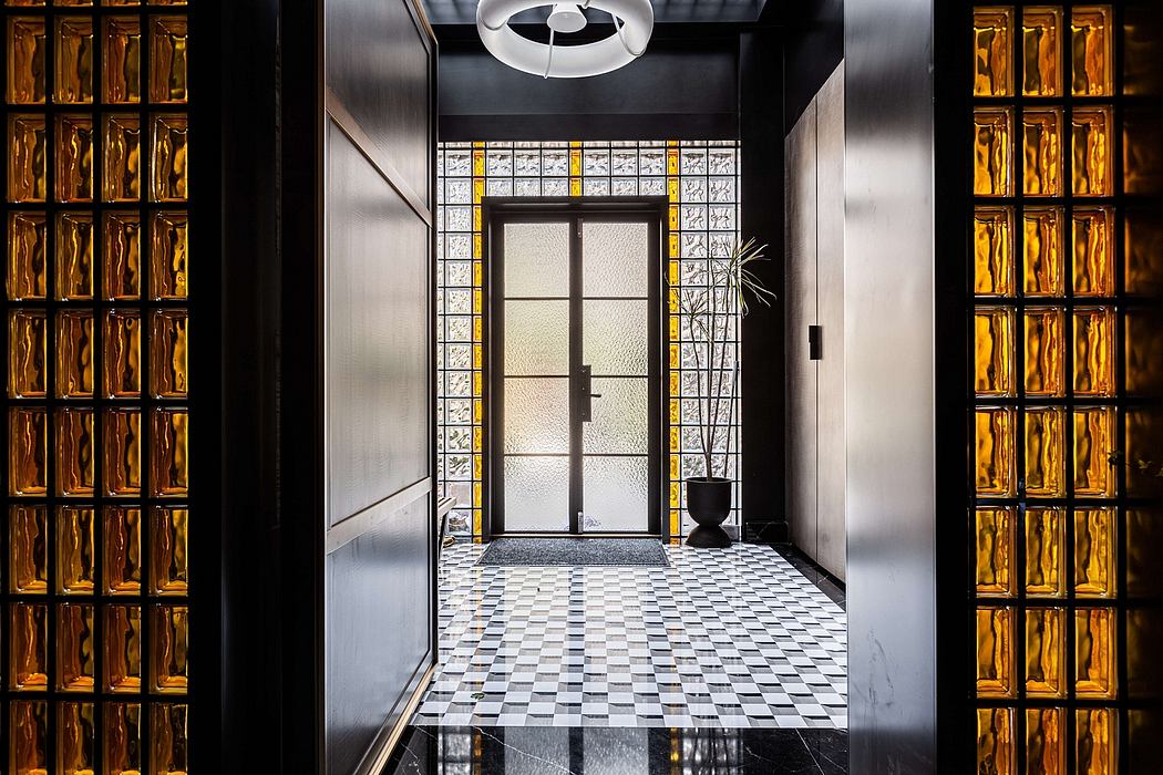 Sleek, modern foyer with geometric tile floor, glass block wall, and ornate lighting fixture.