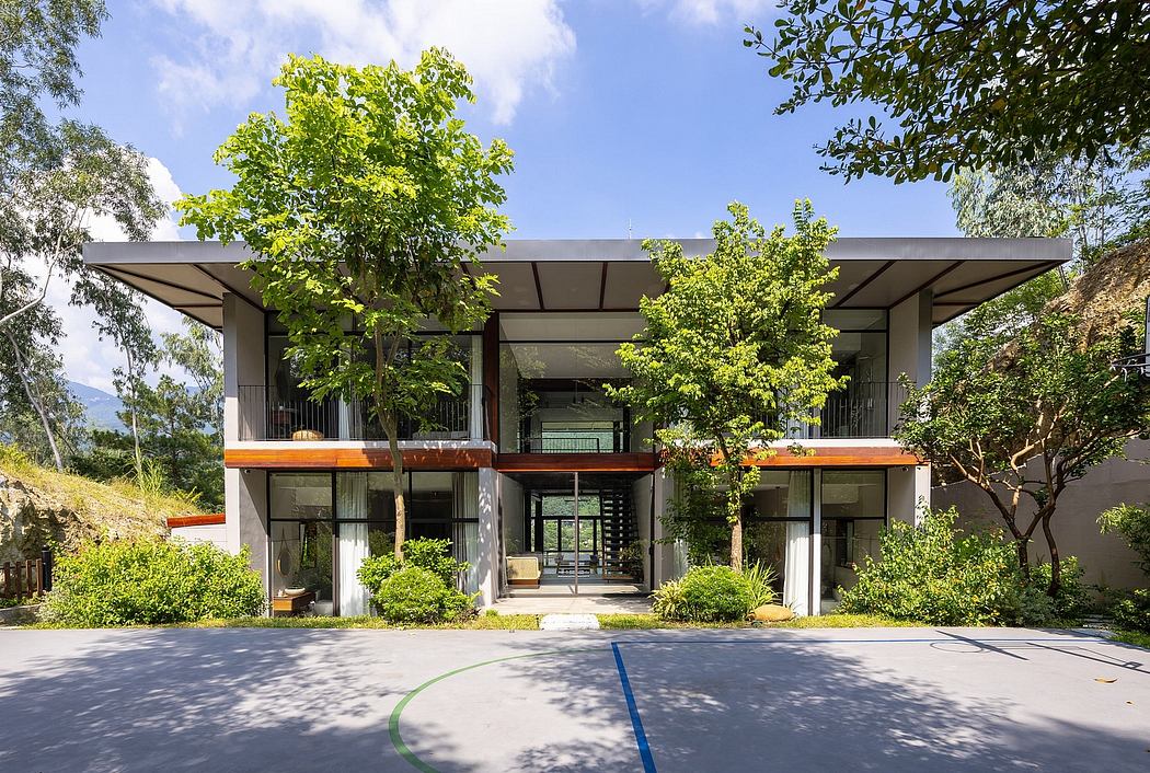 Modern two-story building with a covered patio, wooden accents, and lush greenery surrounding it.