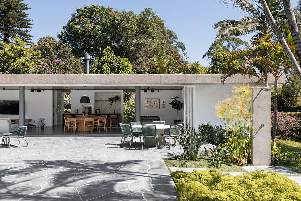 Modern outdoor patio with lush greenery, sleek furniture, and an open interior.