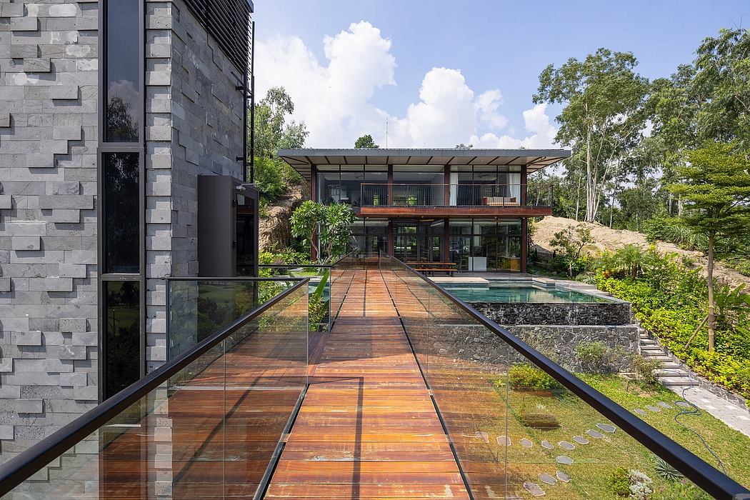 Sleek, modern house with glass walls, wooden walkway, and an inviting swimming pool.
